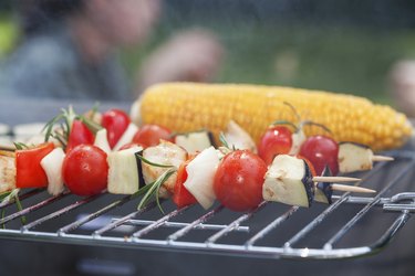 Closeup of shish kebab food stick and ear of corn on a grill