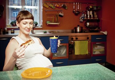 Pregnant woman with cake in kitchen