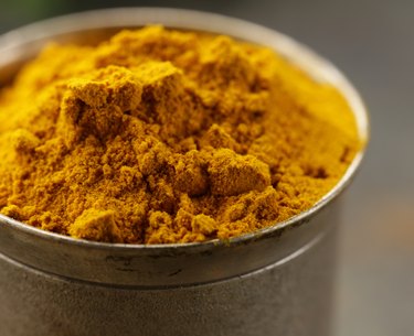 curcuma spice in metal bowl macro shot soft focus