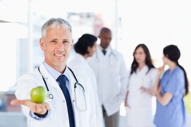 Mature doctor holding an apple in his right hand