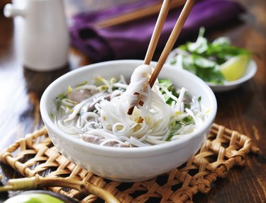 picking up noodles out of a bowl of pho