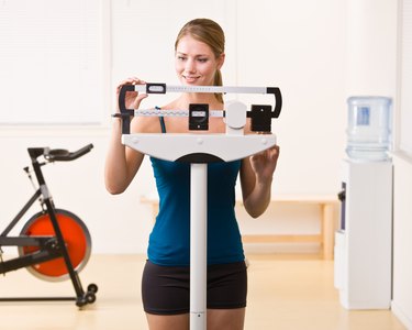 Woman weighing herself on scales in health club