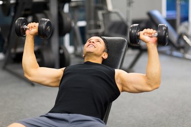 middle aged man lifting weights in gym