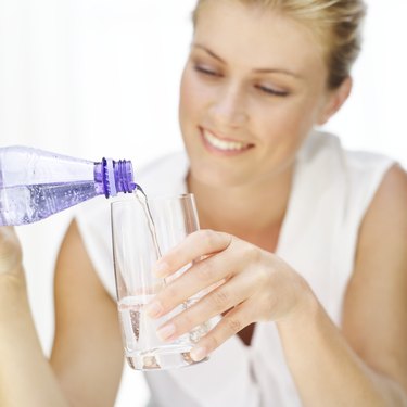 woman pouring water from a bottle into a glass
