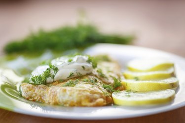 Tilapia with tartar sauce, herbs and lemon on white plate to show pregnancy and tilapia