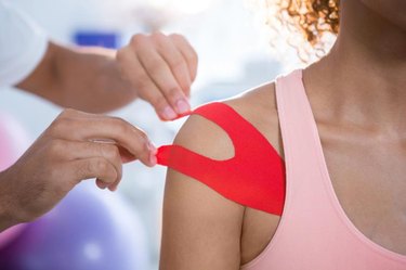 Physiotherapist sticking tape on female patient in clinic