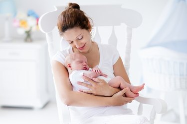 Young mother and newborn baby in white bedroom