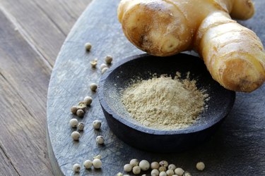 ground ginger (spice) and fresh on a wooden board