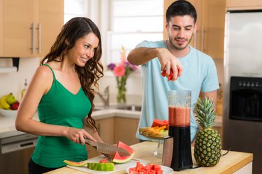 Couple lovers man woman make a smoothie fresh fruits blender