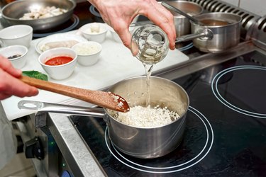 Chef is adding white wine to risotto