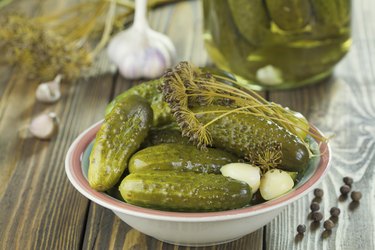 A bowl of pickles with garlic and dill.