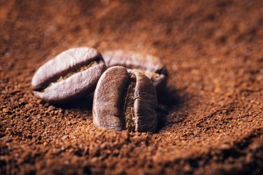 Close up of three beans on ground coffee background
