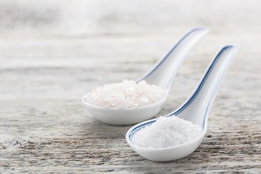 Two tablespoons of salt on a wooden table, for people who need sodium supplements