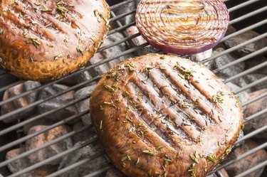 Two portobello mushrooms grilling with purple onion