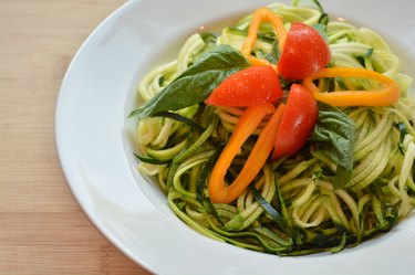 Raw zucchini spaghetti with basil, tomato and yellow pepper