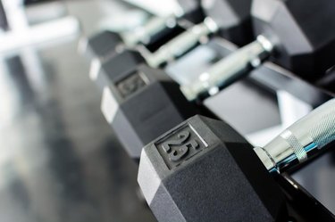 Close up on rows of dumbbells on a rack in a gym.