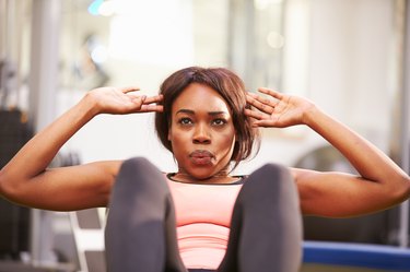 Young woman doing crunches in a gym, close up