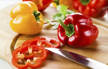 Organic paprika peppers with slice over wooden table