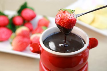 Dipping strawberries into thin dipping chocolate fondue