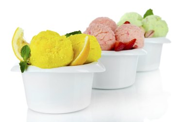 Scoops of carb-containing ice cream or frozen yogurt scoops in bowls, isolated on white.