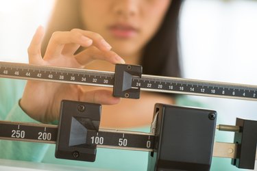 Midsection Of Woman Adjusting Weight Scale