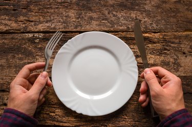 man holding a knife and fork next to the plate