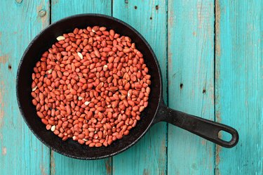 Whole fried pink peanuts in black cast iron pan
