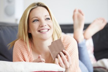 Teenage Girl Eating Bar Of Chocolate At Home