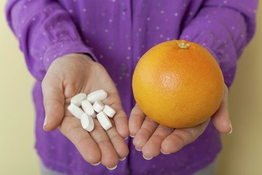 Woman hand with pills medicine tablets and grapefruit