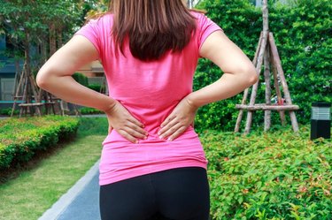 Female athlete lower back painful injury. Sporty woman backache and injury.