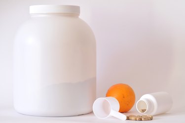 Big jar of protein powder, bottle of pills, orange