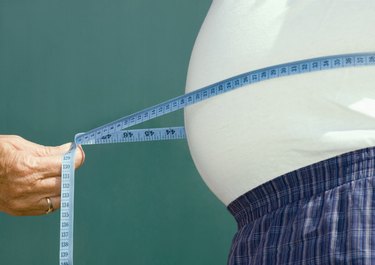 Senior woman measuring stomach of senior man, mid section