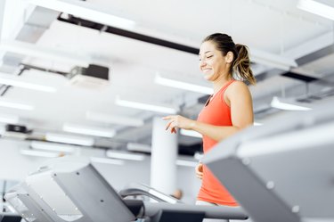 Beautiful young woman running on a treadmill in gym