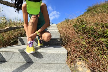 young woman runner hold her sports injured ankle