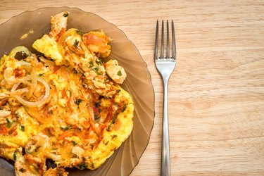 omelette with onion, tomatoes, chicken and parsley on a dish