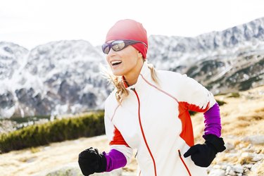 Happy woman running in mountains, sunny day