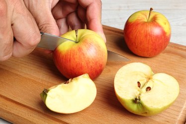 hand slicing apples on wooden cutting board