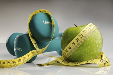 healthy apple, measuring tape and dumbbells