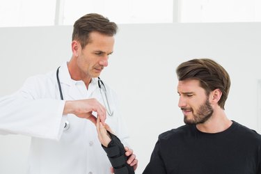 Male physiotherapist examining a young man's wrist in