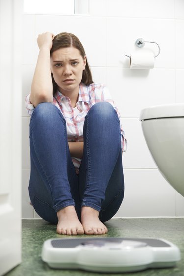 Unhappy Teenage Girl Looking At Bathroom Scales