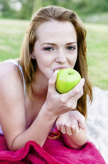 Healthy woman eats apple outdoors