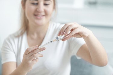 Woman filling insulin syringe with drug