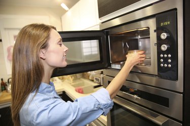 Woman using a microwave in kitchen