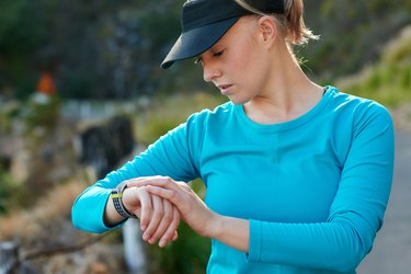 Fit, caucasian woman checking the time during a training run