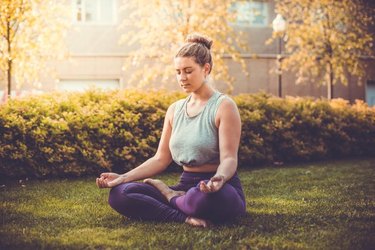 Yoga meditation in lotus pose in park.  Young woman in peace, soul and mind zen balance concept. Toned picture