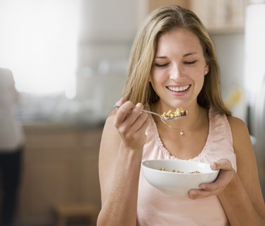 Beautiful young woman holding bowl with cereal smiling