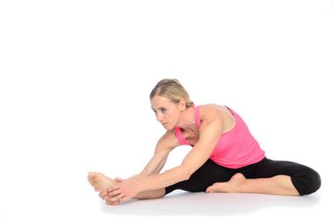 Single gorgeous woman in pink and black outfit doing hamstring stretch over white background with set down shadow