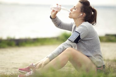 Female Jogger Resting and Drinking Bottled Water