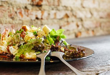 Caesar salad on grunge wooden table and brick wall