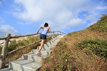 young fitness woman trail runner running up on mountain stairs